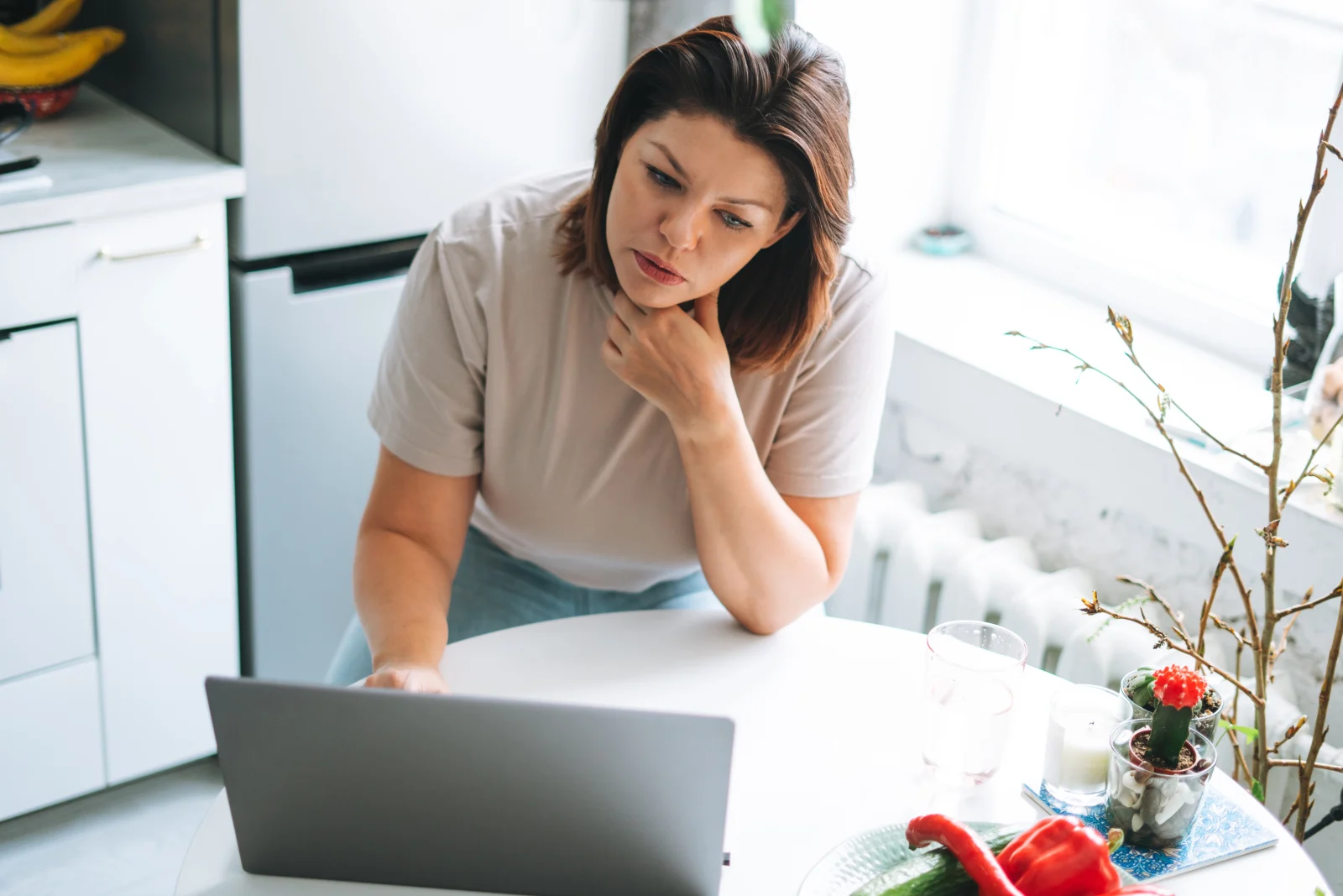 Woman reading on her laptop at the kitchen table – online psychiatry in Grand Rapids, MI